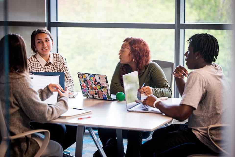 A group of students work together on their laptops in Pius Library